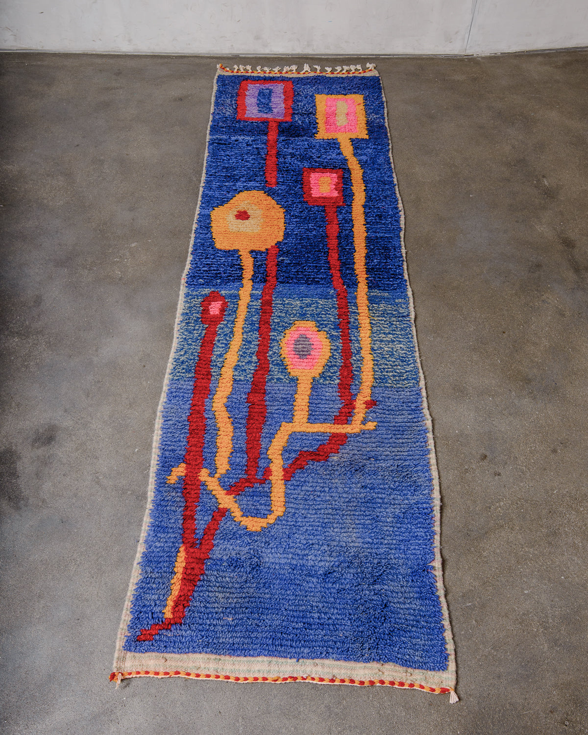 Berberlin vintage runner rug made of brightly coloured wool, laying flat on concrete floor.